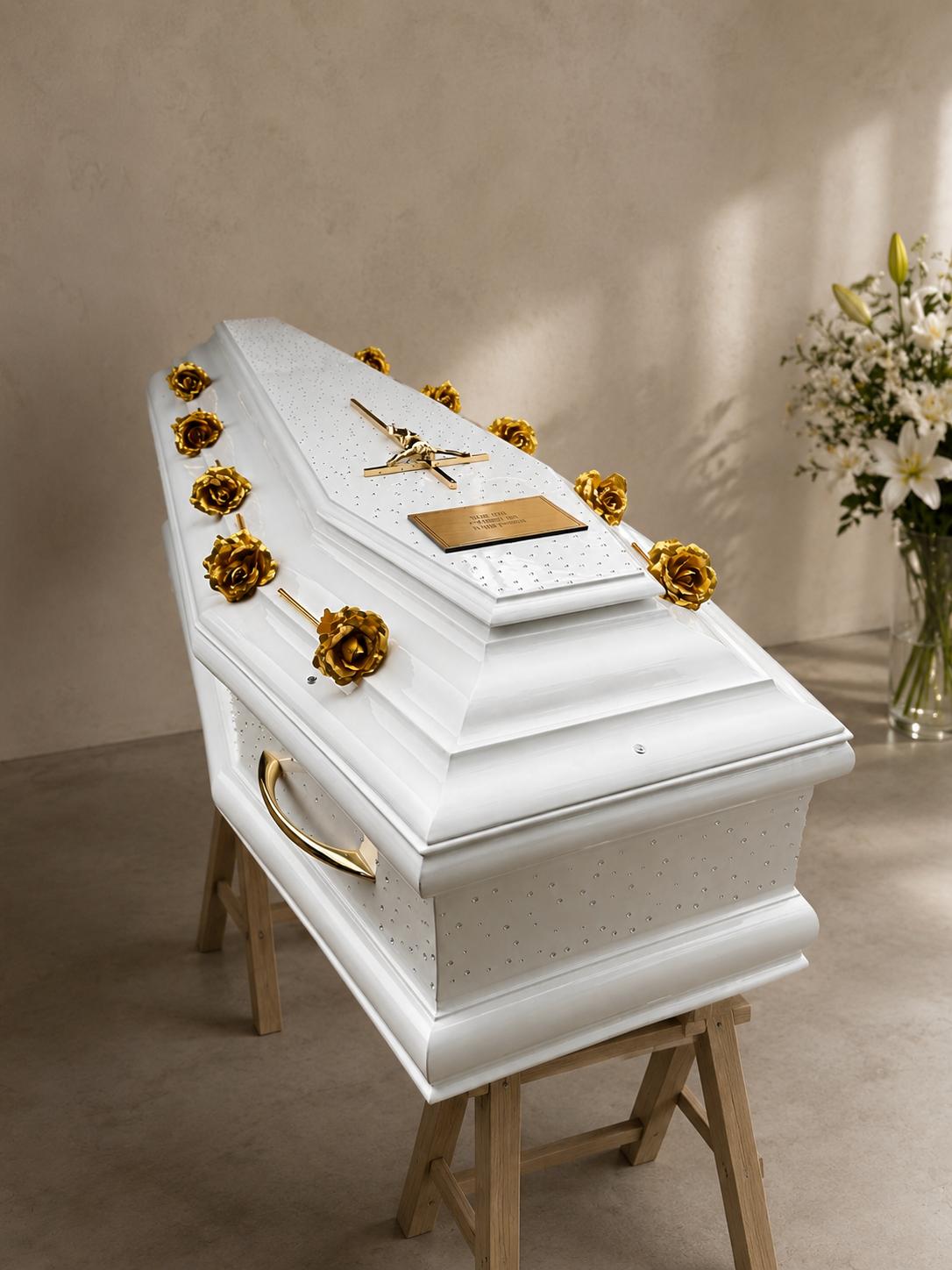 Cercueil laqué blanc orné de roses dorées et d'un christ doré, avec bouquet de lys blancs
